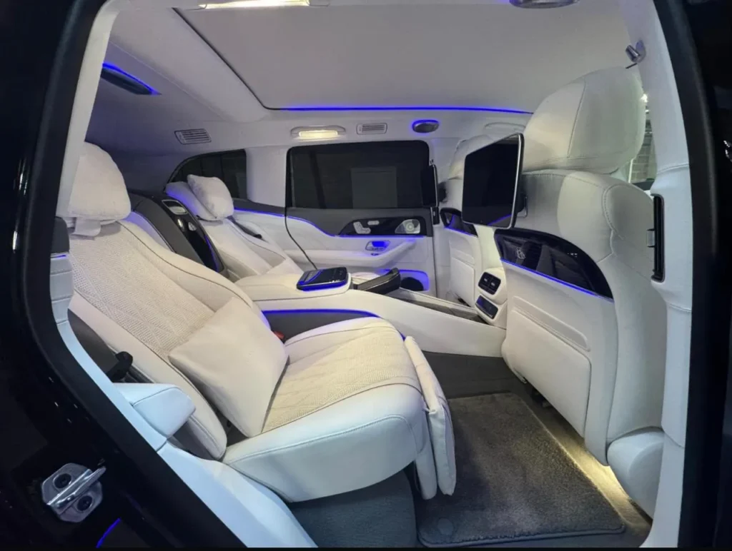 Mercedes-Maybach GLS rear cabin with two white leather executive seats, rear entertainment screens and blue ambient lighting