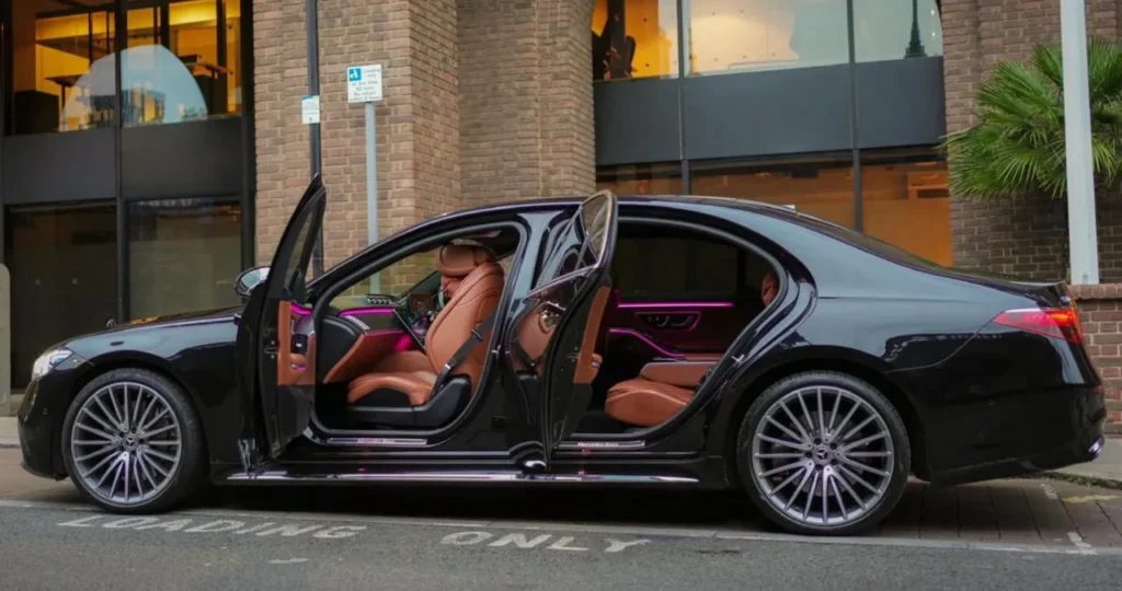 Black Mercedes S-Class chauffeur car in London with front and rear doors open showing tan leather seats