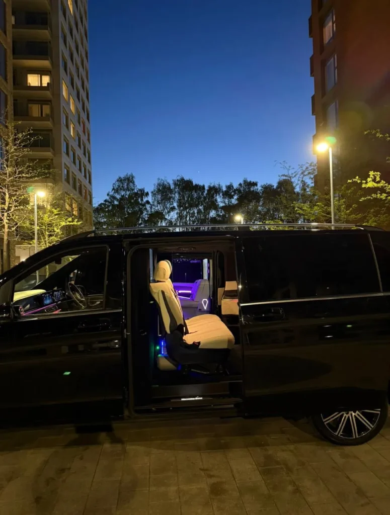 Black Mercedes V-Class chauffeur MPV in London at night with sliding door open and ambient-lit interior
