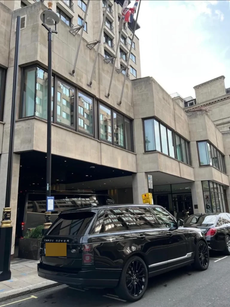 Rear view of a black Range Rover Vogue chauffeur SUV parked outside a central London hotel