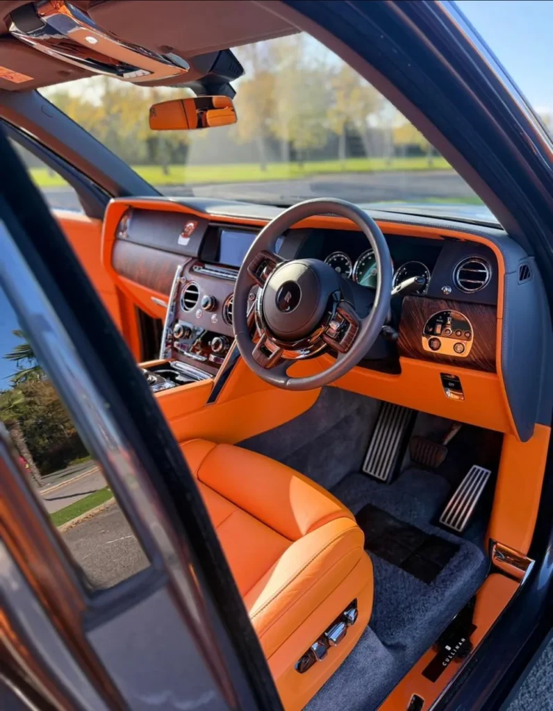 Rolls-Royce Cullinan interior with orange leather, wood veneer dashboard and Rolls-Royce steering wheel